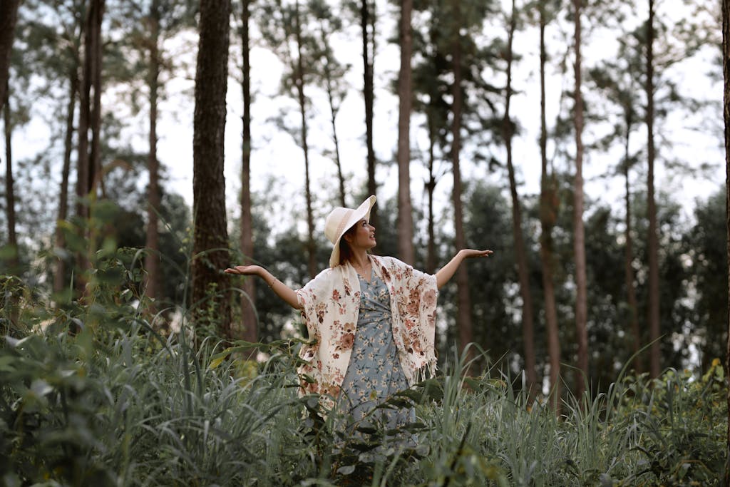 Woman in floral dress and hat exploring lush forest in Vietnam.
